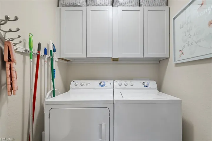 Laundry area with separate washer and dryer and cabinets