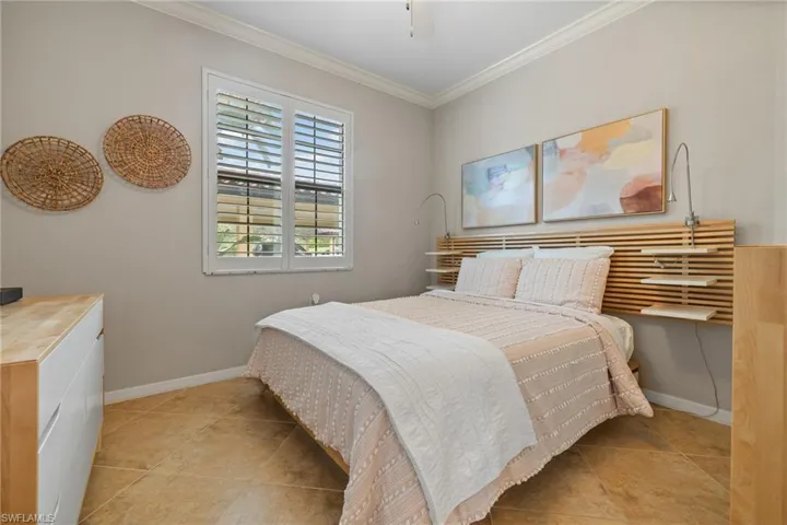 Tiled bedroom featuring ceiling fan and crown molding