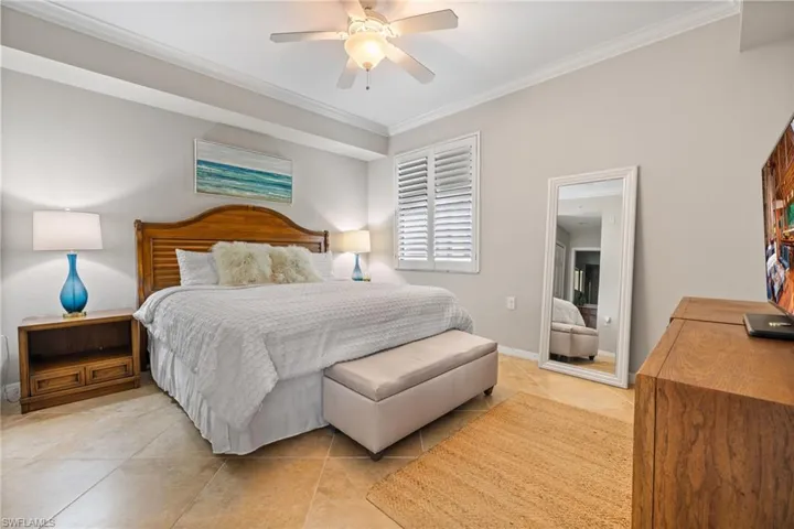 Bedroom with ceiling fan, crown molding, and light tile patterned floors