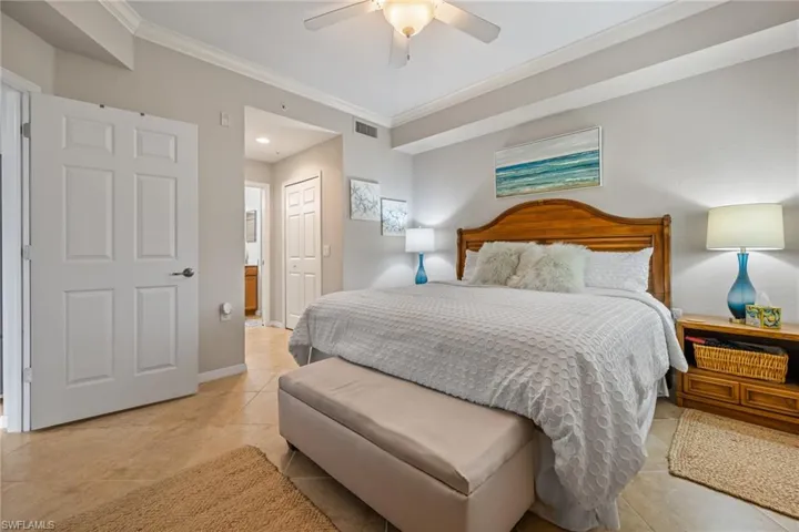 Bedroom with light tile patterned floors, ceiling fan, a closet, and ornamental molding