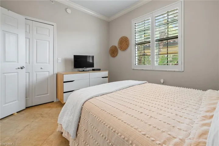 Bedroom featuring light tile patterned floors, a closet, and crown molding