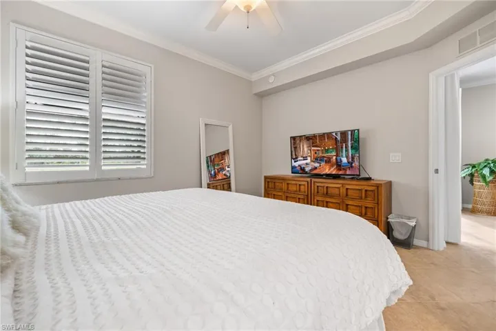 Tiled bedroom with ornamental molding and ceiling fan