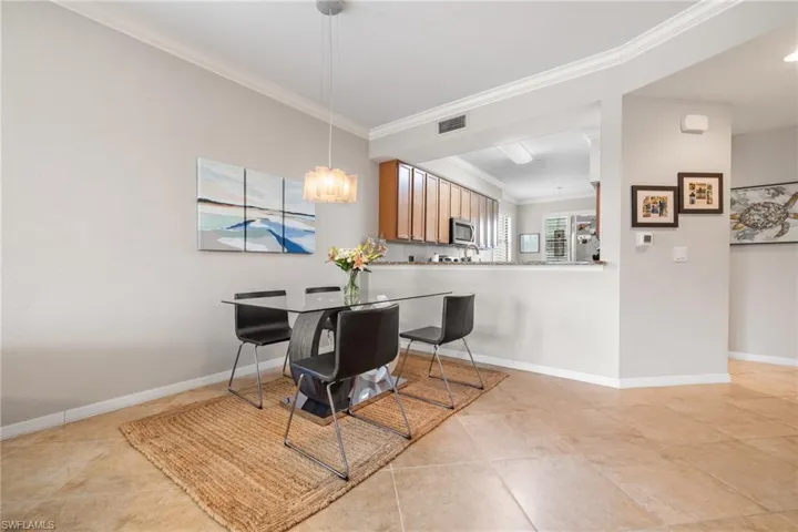 Tiled dining space featuring an inviting chandelier and crown molding