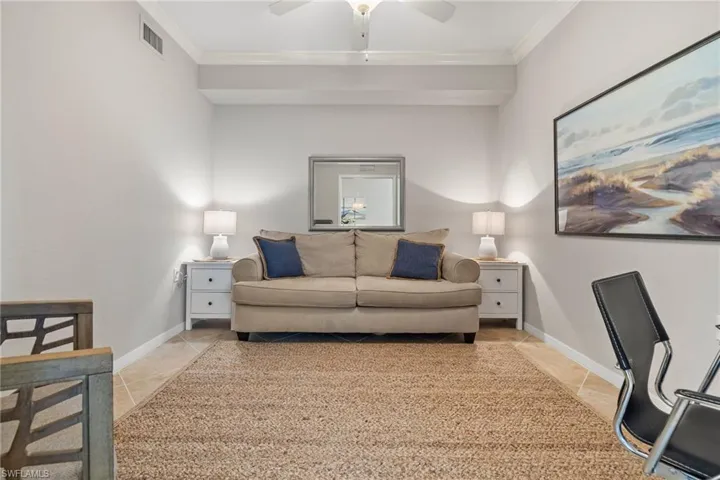 Tiled living room featuring ceiling fan and crown molding