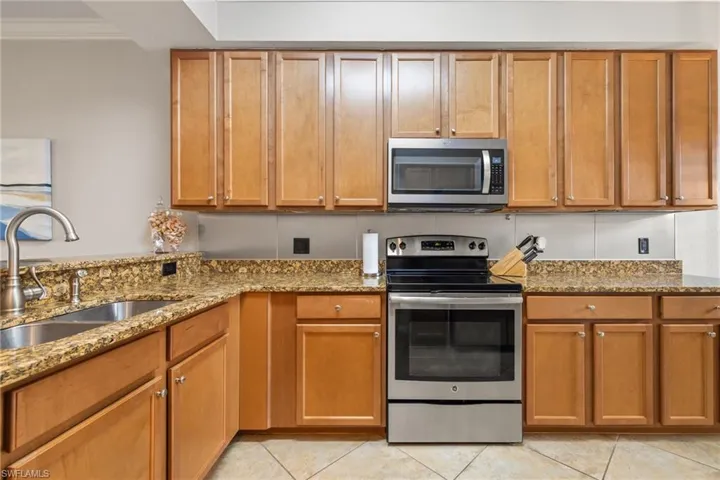 Kitchen featuring stone countertops, sink, crown molding, and stainless steel appliances