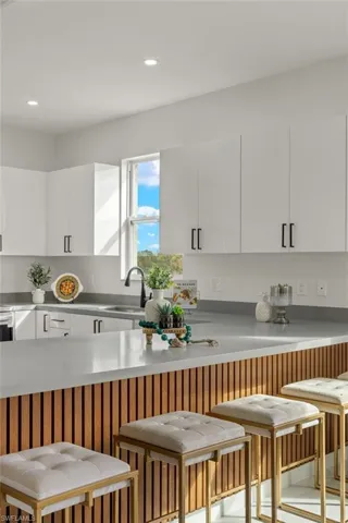 Kitchen with white cabinets, sink, and a kitchen breakfast bar