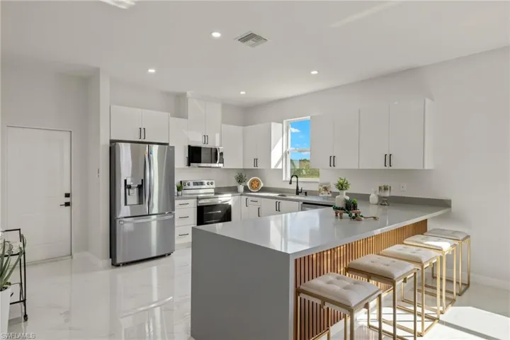 Kitchen featuring sink, kitchen peninsula, a kitchen breakfast bar, white cabinetry, and stainless steel appliances