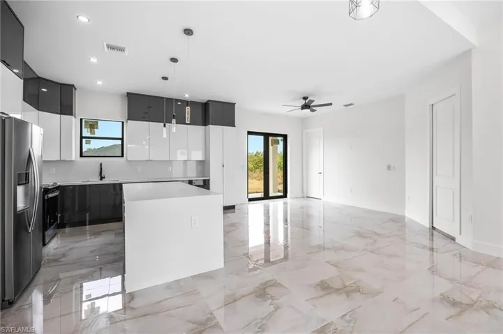 Kitchen featuring appliances with stainless steel finishes, ceiling fan, sink, pendant lighting, and a center island