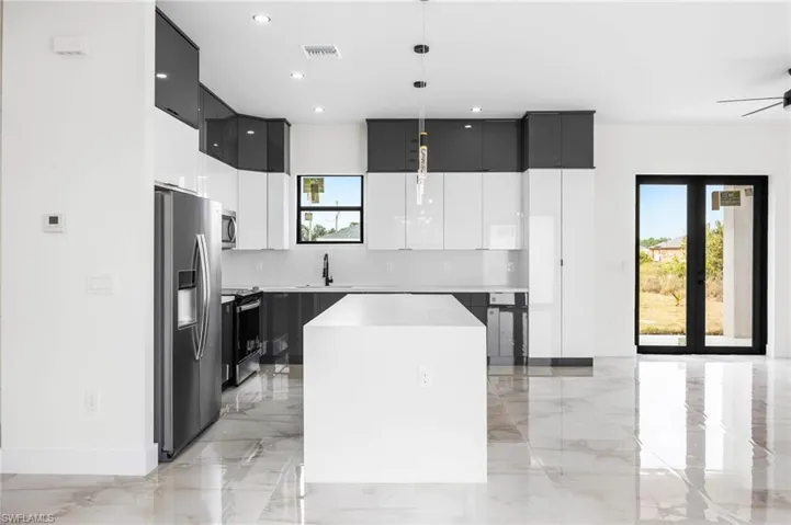 Kitchen with stainless steel appliances, ceiling fan, sink, decorative light fixtures, and a kitchen island