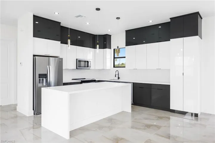 Kitchen with sink, a kitchen island, stainless steel appliances, and decorative light fixtures