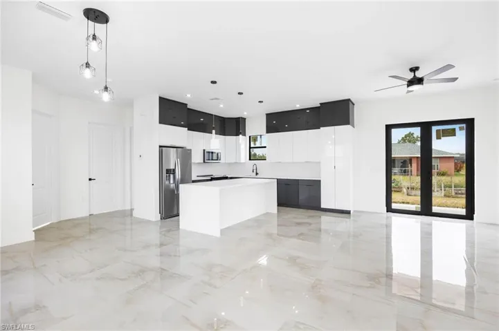 Kitchen featuring sink, hanging light fixtures, ceiling fan, appliances with stainless steel finishes, and a kitchen island