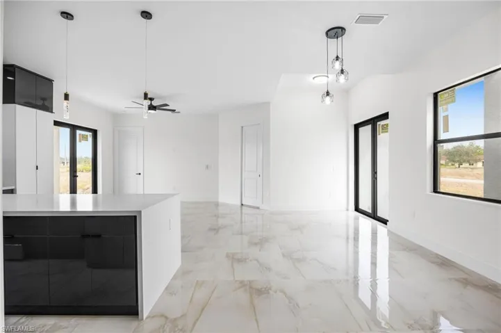 Kitchen with decorative light fixtures, ceiling fan, a healthy amount of sunlight, and a large island