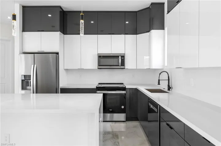 Kitchen featuring white cabinetry, sink, pendant lighting, and appliances with stainless steel finishes