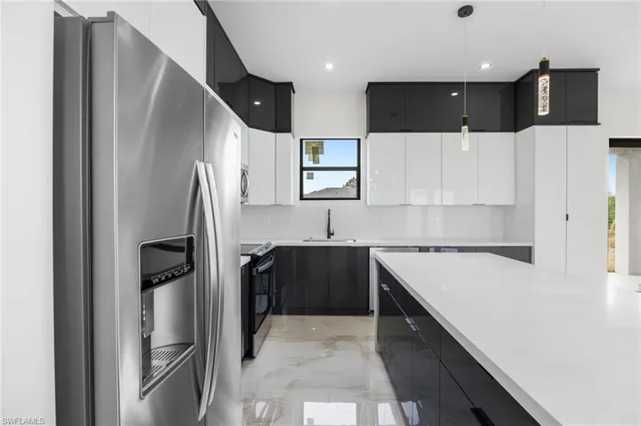 Kitchen with appliances with stainless steel finishes, white cabinetry, hanging light fixtures, and sink