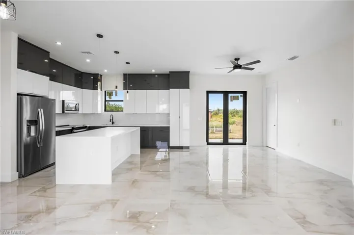 Kitchen featuring ceiling fan, sink, decorative light fixtures, a kitchen island, and appliances with stainless steel finishes