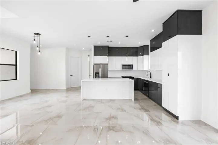 Kitchen with appliances with stainless steel finishes, a center island, hanging light fixtures, and sink