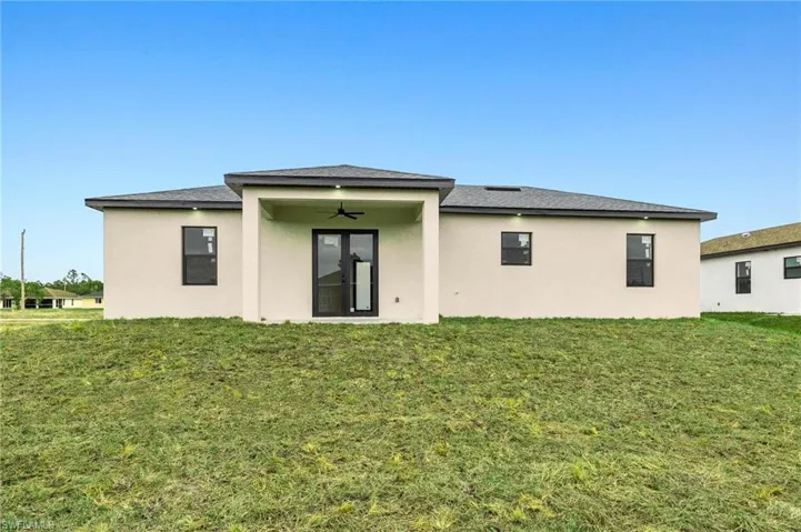 Rear view of property featuring ceiling fan and a lawn