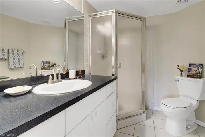 Bathroom featuring tile patterned floors, walk in shower, vanity, and toilet