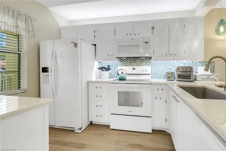 Kitchen with light wood-type flooring, white appliances, a wealth of natural light, and sink