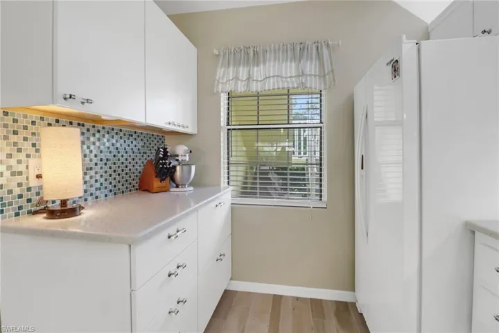 Kitchen featuring light hardwood / wood-style floors, white fridge, tasteful backsplash, and white cabinetry