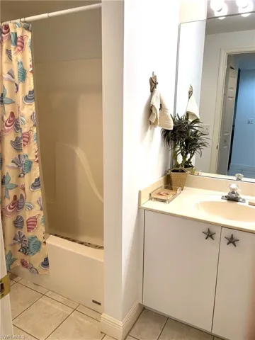 Bathroom with tile patterned flooring, shower / bath combination with curtain, and vanity