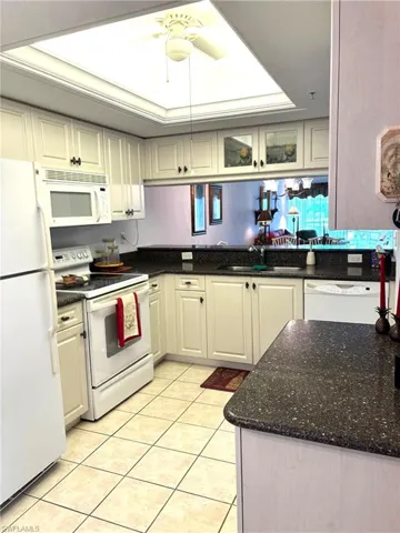 Kitchen featuring white appliances, white cabinetry, sink, kitchen peninsula, and light tile patterned flooring