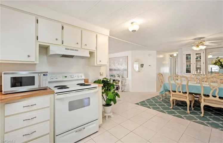 Kitchen featuring white appliances, ceiling fan, white cabinets, and light tile patterned floors