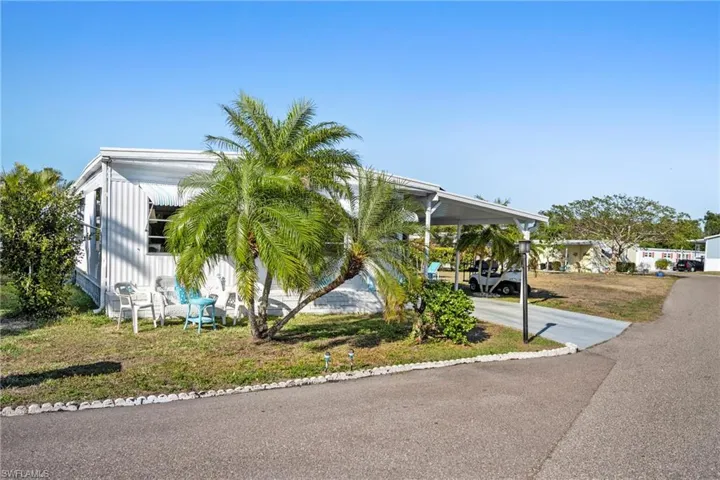 View of front of home with an attached carport, a front lawn, and driveway