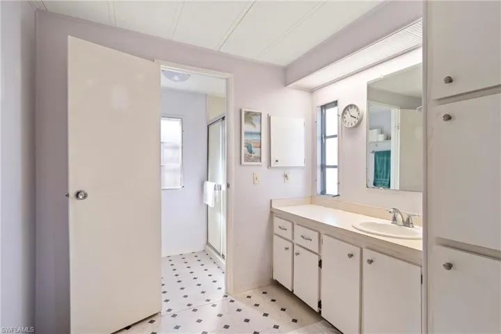 Bathroom featuring a shower stall, vanity, and light floors