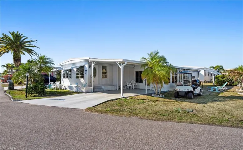 Manufactured / mobile home with a front yard, an attached carport, and driveway