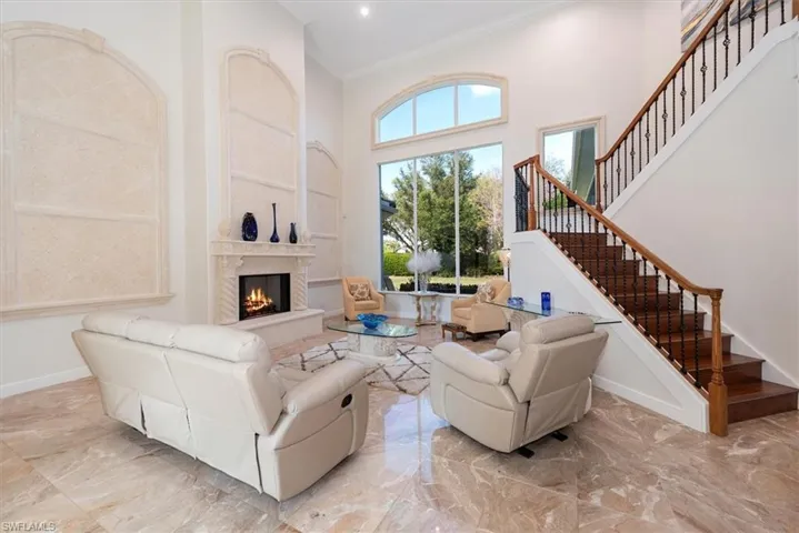 Living room with a high ceiling, ornamental molding, a premium fireplace, and marble tiled flooring