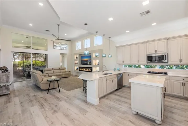 Kitchen featuring pendant lighting, open floor plan, a center island, ornamental molding, and ceiling fan