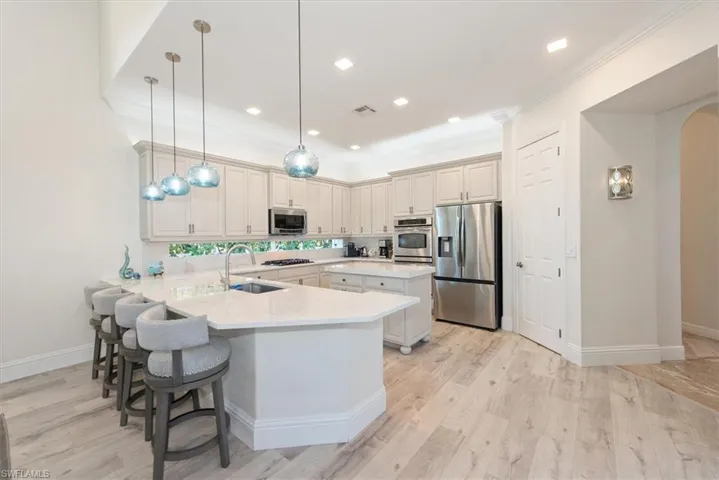 Kitchen featuring stainless steel appliances, a kitchen breakfast bar, pendant lighting, a peninsula, and arched walkways