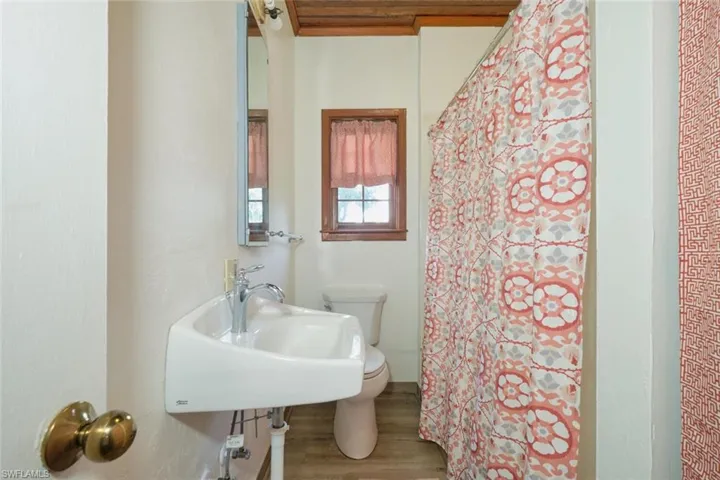 Bathroom with hardwood / wood-style flooring, wood ceiling, toilet, and sink