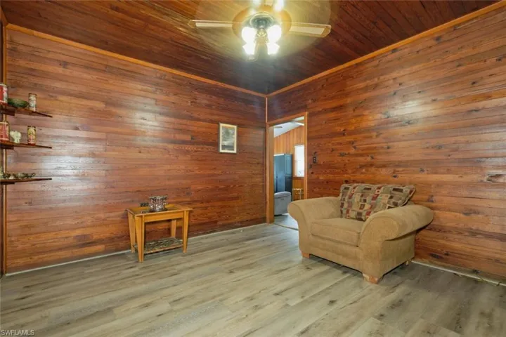 Sitting room featuring ceiling fan, wooden walls, hardwood / wood-style floors, and wood ceiling