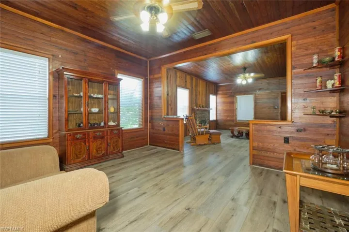 Living area with ceiling fan, wood-type flooring, wooden walls, and wood ceiling