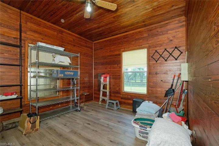 Sitting room with ceiling fan, wooden walls, wood ceiling, and wood-type flooring