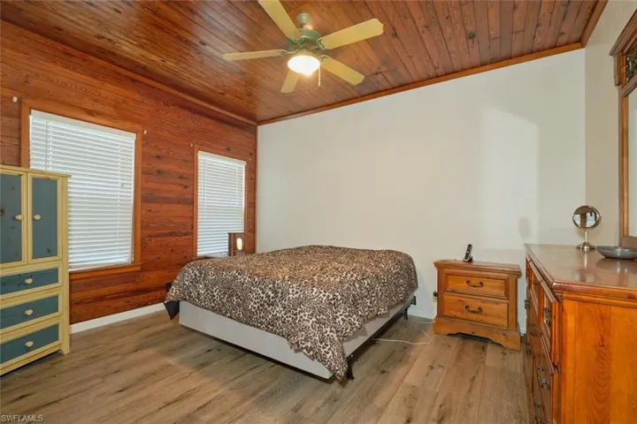 Bedroom with wood walls, wooden ceiling, ceiling fan, and hardwood / wood-style floors