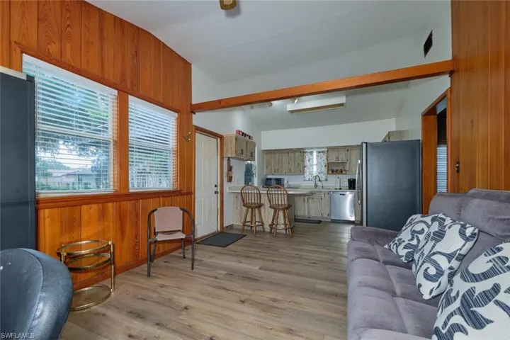 Living room featuring sink, lofted ceiling, and light hardwood / wood-style floors