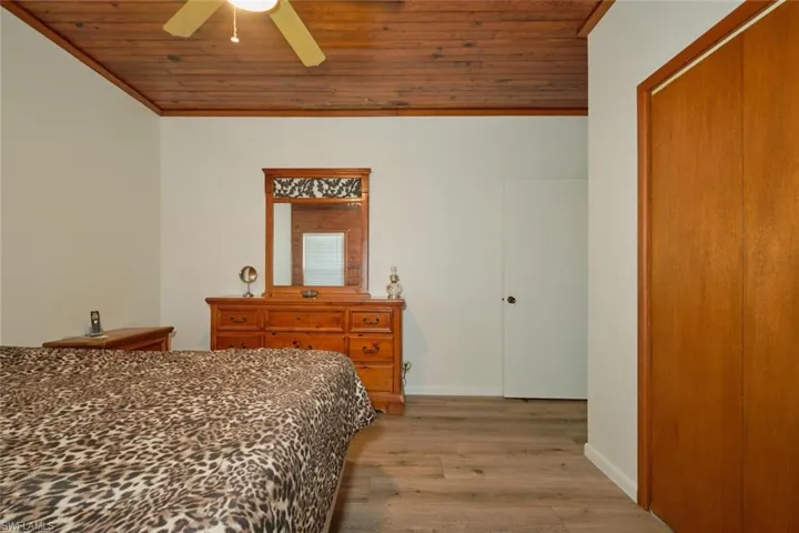 Bedroom with ceiling fan, ornamental molding, wooden ceiling, and wood-type flooring