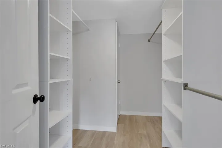 Huge walk-in closet featuring light wood-style floors