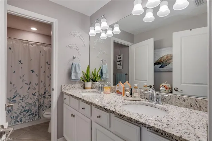 Second floor bathroom featuring double vanity, a shower with shower curtain,and light tile patterned floors