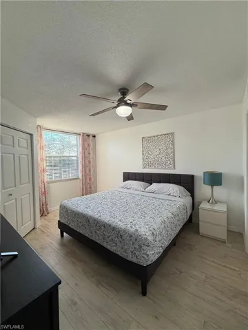 Bedroom with a closet, light wood-style flooring, a ceiling fan, and a textured ceiling
