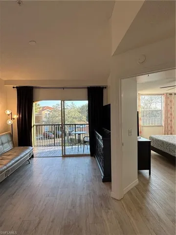 Unfurnished living room with light wood-type flooring, plenty of natural light, lofted ceiling, and a textured ceiling