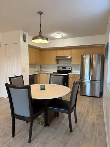 Kitchen featuring freestanding refrigerator, hanging light fixtures, light countertops, electric range, and decorative backsplash