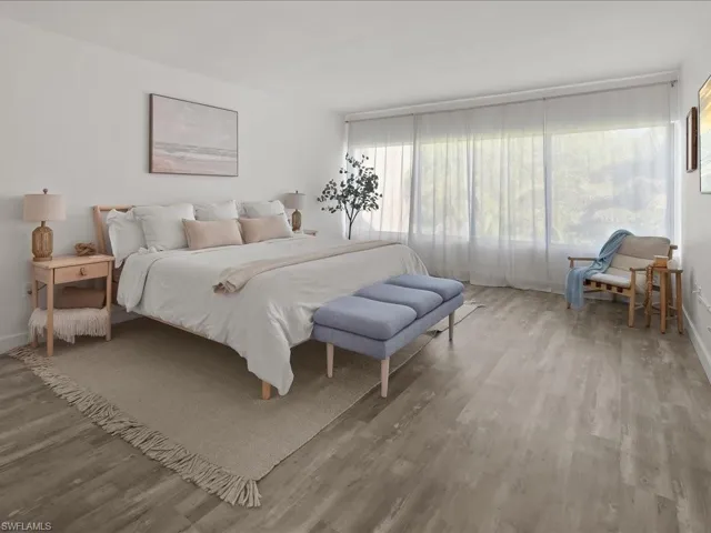 Spacious primary bedroom has abundent light from the wall of windows.