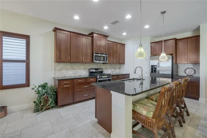 Kitchen with dark stone countertops, appliances with stainless steel finishes, healthy amount of natural light, hanging light fixtures, and recessed lighting