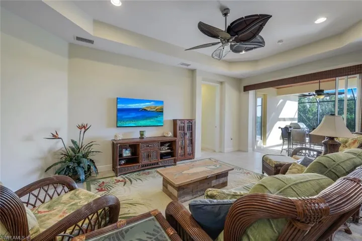 Living room featuring a raised ceiling, ceiling fan, recessed lighting, and a sunroom