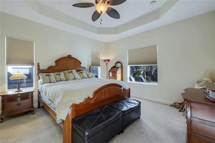 Carpeted bedroom featuring a raised ceiling and a ceiling fan