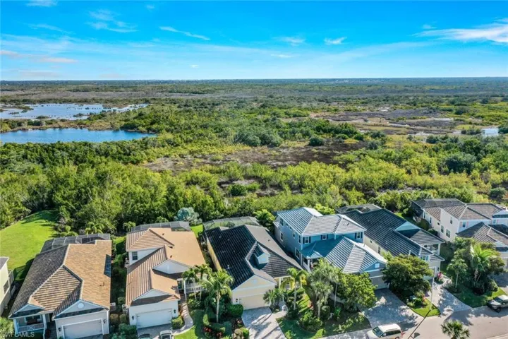Aerial perspective of suburban area featuring a large body of water and a heavily wooded area